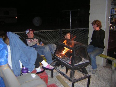 1995 Ford Bronco - People gather around a fire pit on a gravel patio at night.