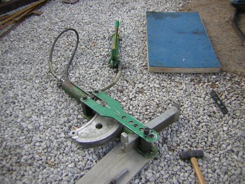 1995 Ford Bronco - Tools including a pipe bender, hammer, and level are laid out on a gravel surface.