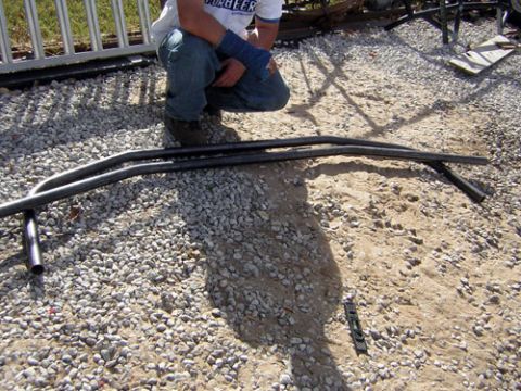 1995 Ford Bronco - Two curved metal tubes are laid out on a gravel surface with a person in the background.