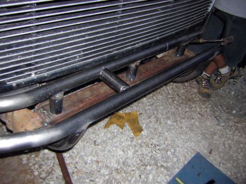 1995 Ford Bronco - A person is welding custom metal tubing onto a vehicle's frame, likely for a bumper or protection.