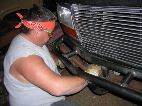 1995 Ford Bronco - A person installs a custom front bumper on a vehicle, with the grille and headlight visible.