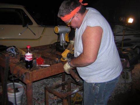 1995 Ford Bronco - Man works on metal fabrication outdoors at night with a grinder.