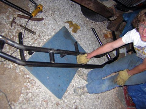 1995 Ford Bronco - A person works on a custom bumper assembly in a garage, surrounded by tools and gravel.