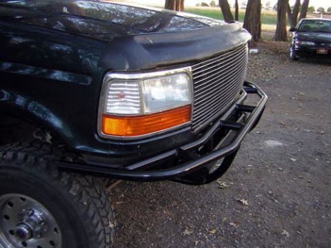 1995 Ford Bronco - A dark green 1992 Ford Bronco is shown from the front with a custom bumper and grille, with another vehicle in the background.