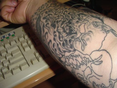 1993 Ford Bronco - A detailed tattoo of flames and a mythical creature adorns an arm, positioned near a computer keyboard.