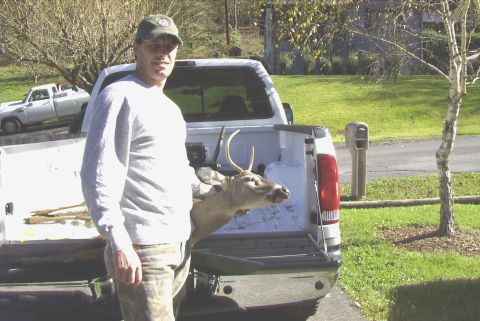 1995 Ford Bronco - Man with harvested deer in the bed of a pickup truck, with another truck visible in the background.