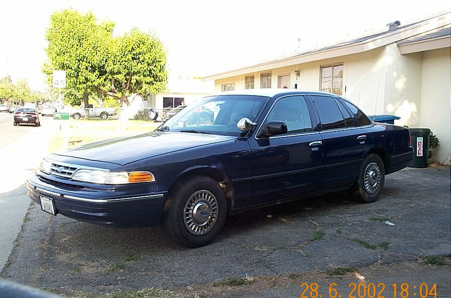 Dark blue Ford Crown Victoria sedan parked in a driveway, front three-quarter driver's side view