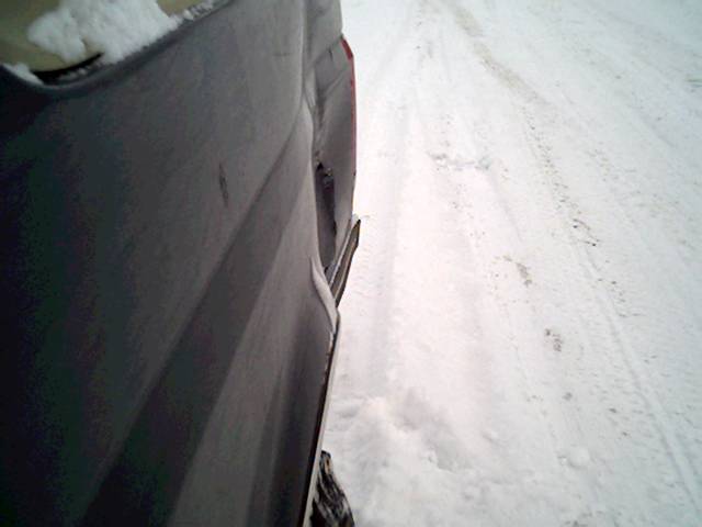 Dark SUV rear quarter panel with snow on the ground