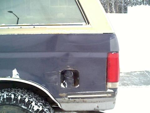 1987 Ford Bronco - Rear view of a damaged 1987 Ford Bronco in a snowy environment.