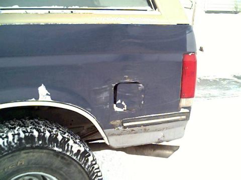 1987 Ford Bronco - The rear quarter panel of a blue 1987 Ford Bronco shows damage to the fuel door and bumper.
