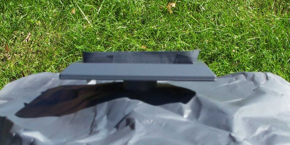 Black plastic automotive vent or trim panel laid on a tarp in green grass