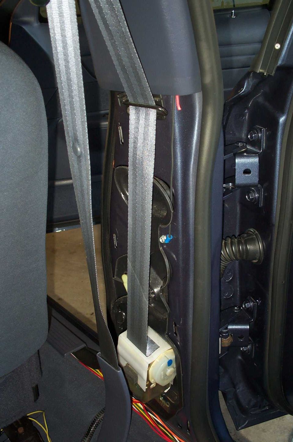 To gain access to the wiring tunnel between the body and the door, you must remove the panel that covers the seat belt track.