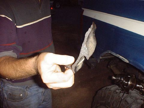 1988 Ford Bronco - A person holds a damaged piece of blue vehicle trim with a white stripe.