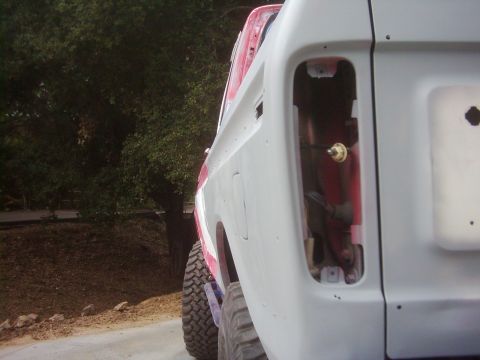 1978 Ford Bronco - A 1978 Ford Bronco is shown in primer gray, missing its rear taillight assembly, with a large off-road tire visible.