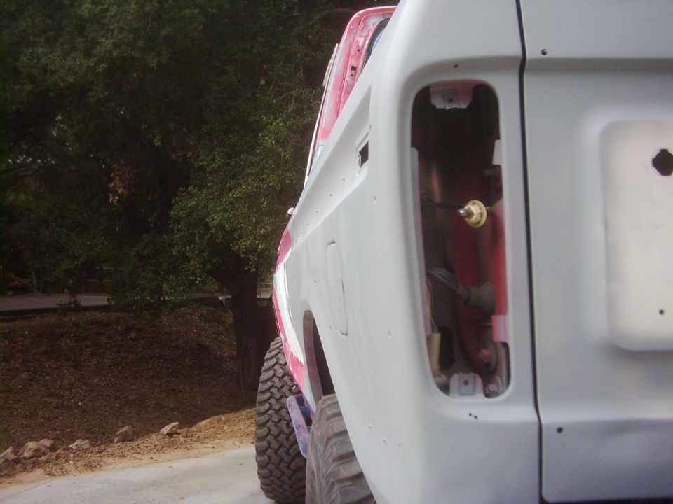 1978 Ford Bronco rear quarter panel, primer gray, missing taillight assembly, large off-road tire visible