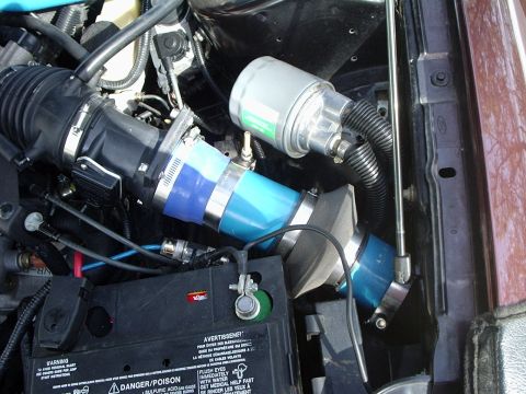2000 Ford Taurus - Aftermarket intake system installed in an engine bay, blue silicone couplers and a cylindrical air filter.