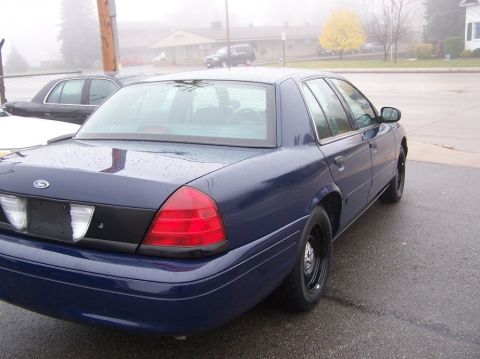 2001 Ford Crown Victoria - Rear view of a blue 2001 Ford Crown Victoria sedan parked on a wet asphalt surface.
