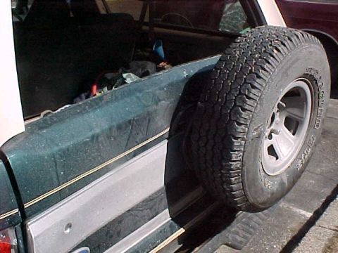 1993 Ford Bronco - Rear view of a green 1993 Ford Bronco, showing the spare tire mounted externally.