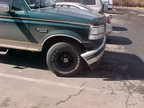 1993 Ford Bronco - A green Ford Bronco is parked next to another vehicle, showing its front quarter panel and wheel.