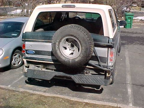 1993 Ford Bronco - The rear of a Ford Bronco SUV is shown, a spare tire and a damaged bumper.