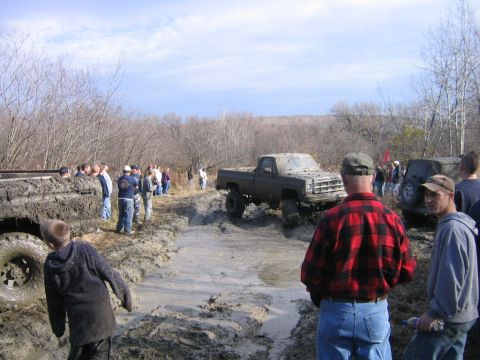 1994 Ford Bronco - Off-road vehicles navigate a challenging mud course with onlookers observing the action.