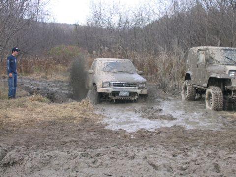 1994 Ford Bronco - Two off-road vehicles are stuck in deep mud during what appears to be a poker run event.