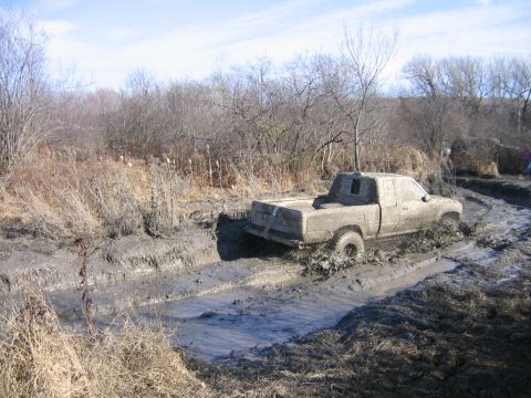 1994 Ford Bronco - A pickup truck struggles through a thick mud bog during an off-road event.