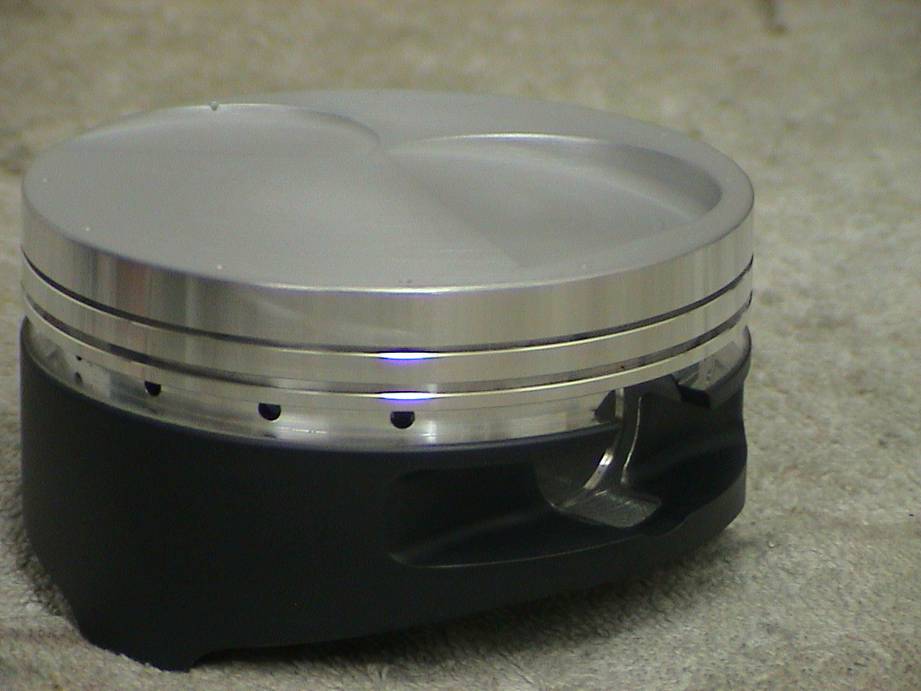 Forged domed piston with black-coated skirt and gas ports, side view