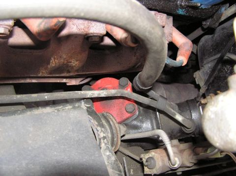 1973 Ford Ranchero - Close-up view of a red component within a vehicle's engine compartment, showing hoses and engine parts.