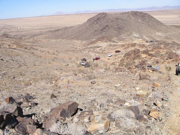 Trucks and SUVs parked on a rocky desert hillside under a clear blue sky