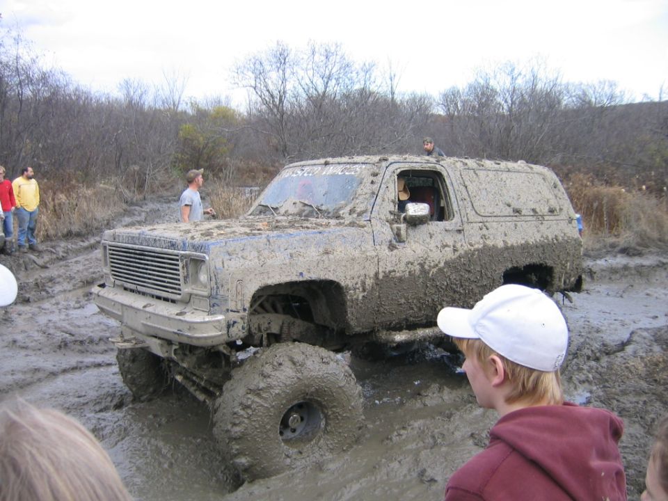 Mud-covered 1973 Chevrolet K5 Blazer stuck in deep mud with people watching