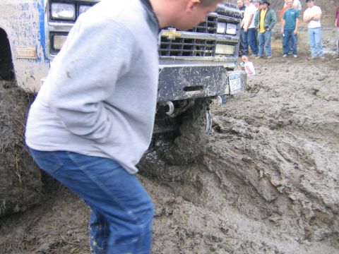 1994 Ford Bronco - A group of people watch as a truck becomes deeply stuck in thick mud.