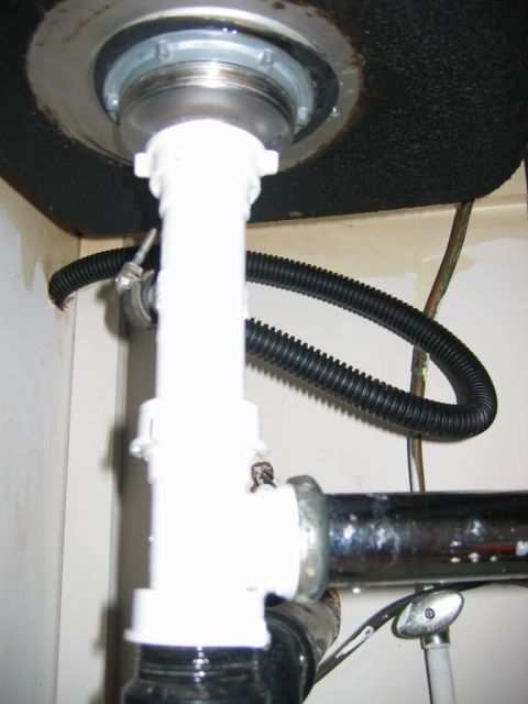 1985 Ford LTD Crown Victoria - Under-sink plumbing with a white PVC drain pipe and a black flexible hose attached to the drain assembly.