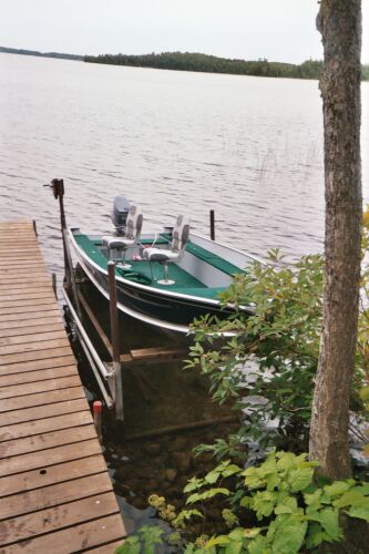 1996 Ford Bronco - A boat is docked on a calm lake next to a wooden pier, with trees and foliage on the shore.