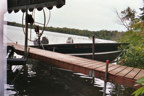 1996 Ford Bronco - A Lund boat is docked on a lake, with a wooden ramp leading to it.