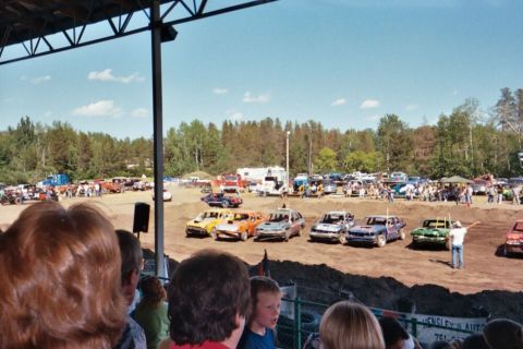 1996 Ford Bronco - Cars are gathered on a dirt track, likely for a demolition derby event, with spectators watching from above.