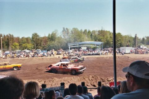1996 Ford Bronco - Cars compete in a demolition derby event with a crowd watching from bleachers.