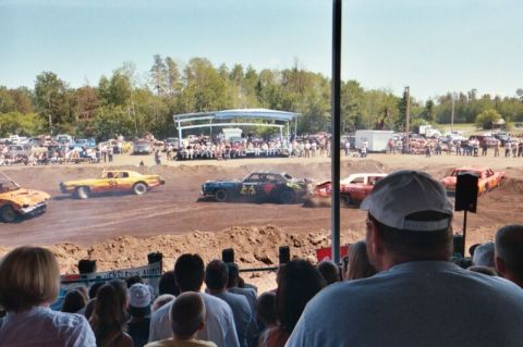 1996 Ford Bronco - Cars are actively competing in a demolition derby event, with a crowd gathered to watch the action.