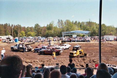 1996 Ford Bronco - A 1996 Ford Bronco is seen in a demolition derby event, surrounded by other vehicles and spectators.