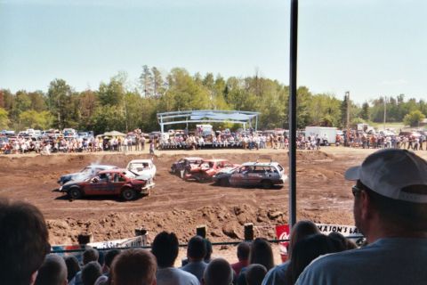 1996 Ford Bronco - Cars compete in a demolition derby event with a crowd watching from the stands.