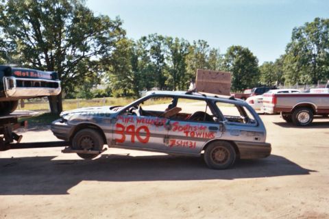 1996 Ford Bronco - A battered station wagon prepared for demolition derby sits on a trailer, with "340" and "Southside Towing" spray-painted on its doors.