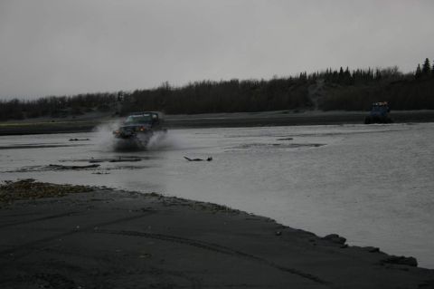 2003 Jeep TJ - A Jeep Wrangler navigates a shallow body of water, with another vehicle in the distance under an overcast sky.