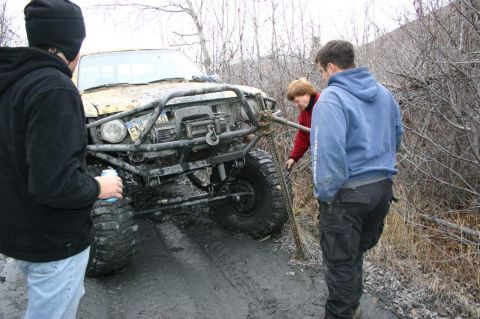 2003 Jeep TJ - Three people attempt to free a heavily modified off-road vehicle stuck deep in mud.