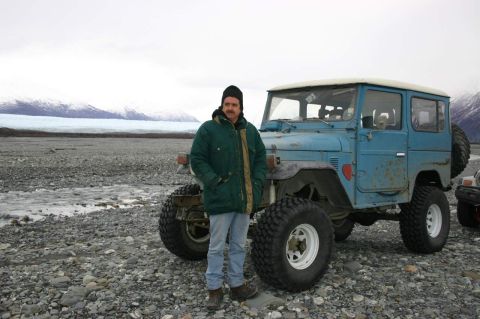 2003 Jeep TJ - A man stands beside a blue Toyota Land Cruiser FJ40 in a rocky, glacial landscape.