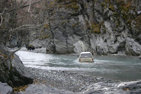 2003 Jeep TJ - Two off-road vehicles navigate a rocky riverbed between steep canyon walls.