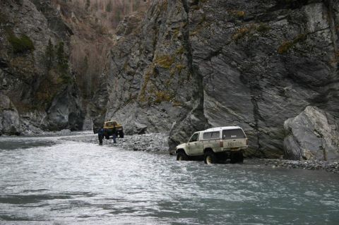 2003 Jeep TJ - Two trucks navigate a rocky riverbed within a canyon, with one Toyota pickup clearly visible in the foreground.