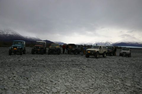 2003 Jeep TJ - Group of off-road vehicles gathered on a rocky plain with a backdrop of snow-covered mountains.
