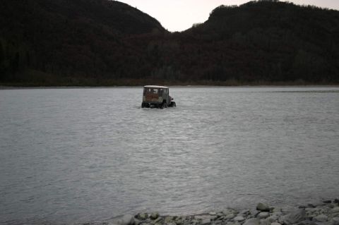 2003 Jeep TJ - A Jeep Wrangler navigates a wide, shallow river under an overcast sky.