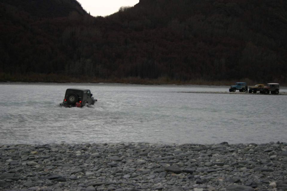 Jeep Wrangler driving through shallow water, other vehicles in distance