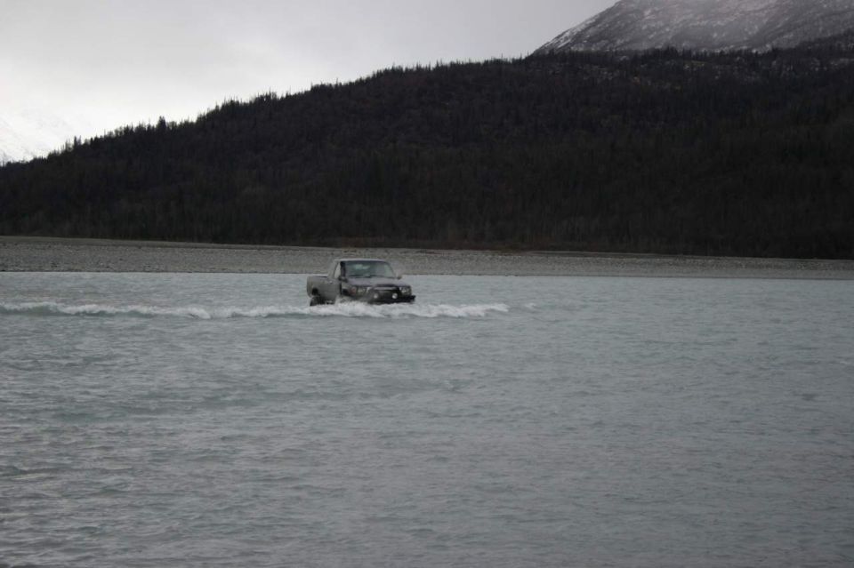 Gray pickup truck driving through shallow water, front view